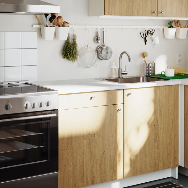 A stylish KNOXHULT base cabinet in light wood with a drawer and doors, set in a modern kitchen with white tiles.
