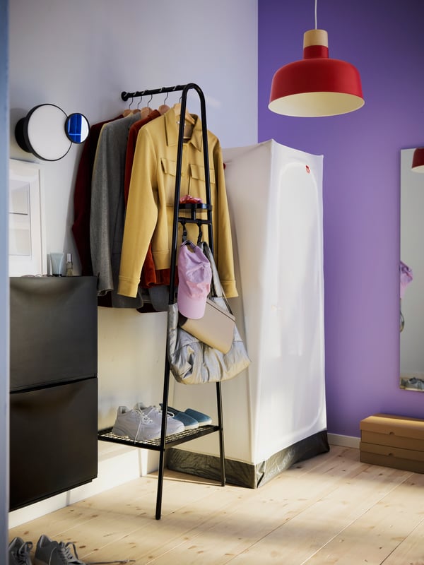 Corner of a room with white and purple walls, an ÄLGANÄS stand and a VUKU cabinet. Red BUNKEFLO pendant lamp.