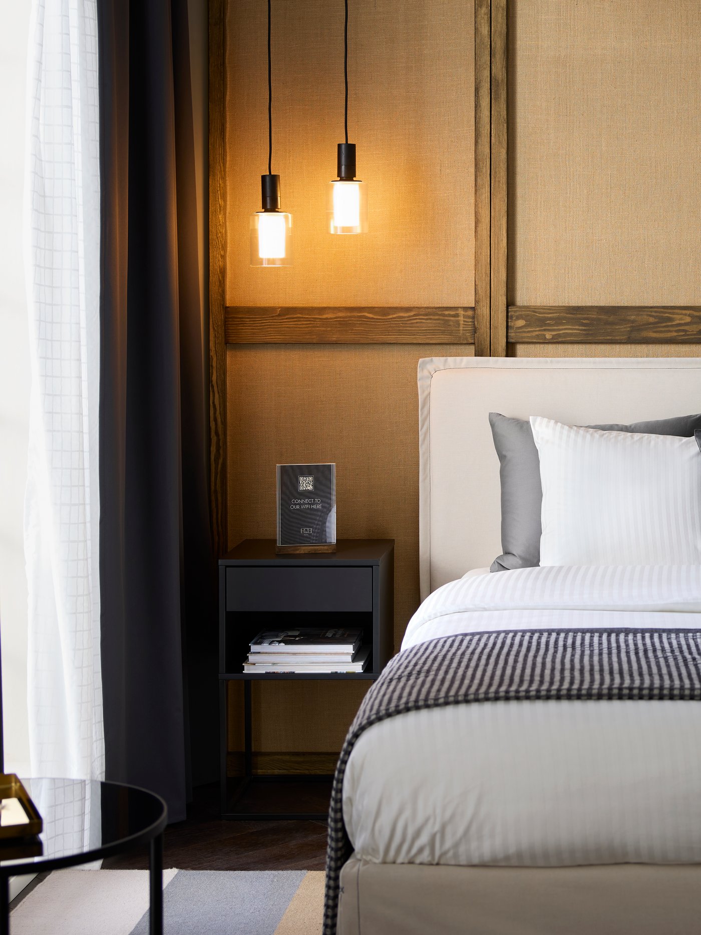 A beige TÄRNKULLEN upholstered bed frame accents a freshly made hotel bed on a wall below a zebra artwork, by a nightstand.
