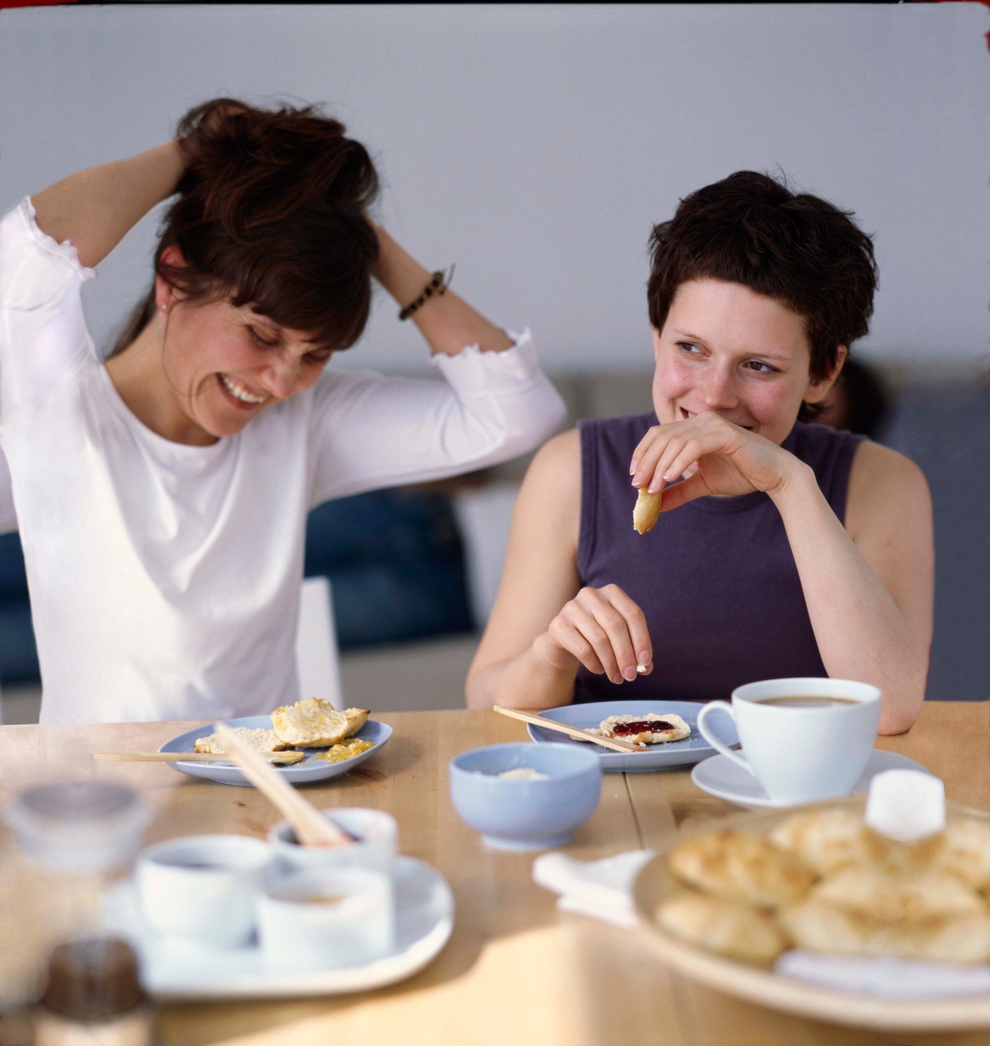 Two people enjoying breakfast at the breakfast table with coffee, yoghurt and other items.