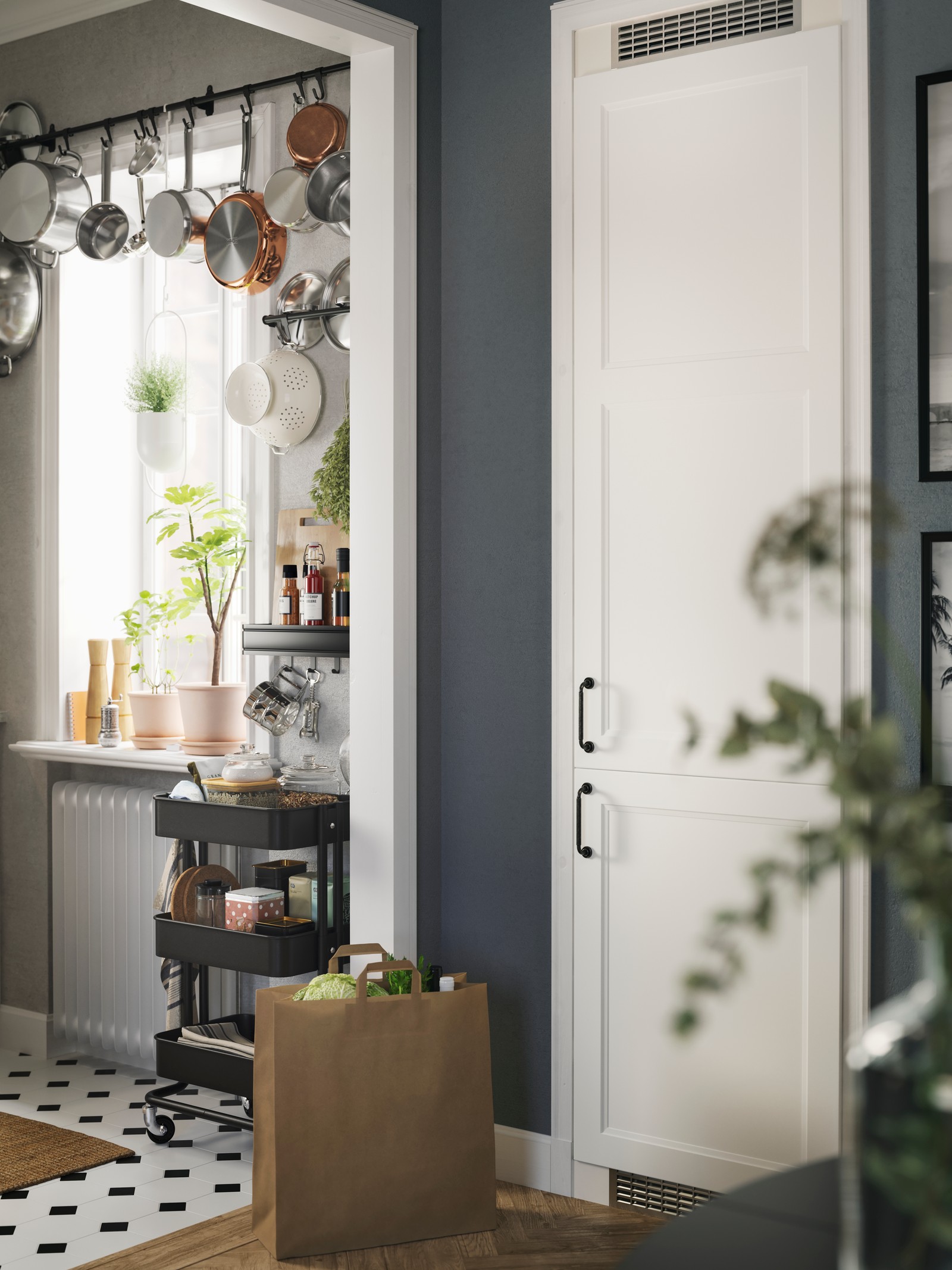 Lonci i tiganji vise sa zida iznad prozora sa zasađenim biljkama i tamnosiva kuhinjska kolica u blizini u kuhinji u tradicionalnom deko stilu.