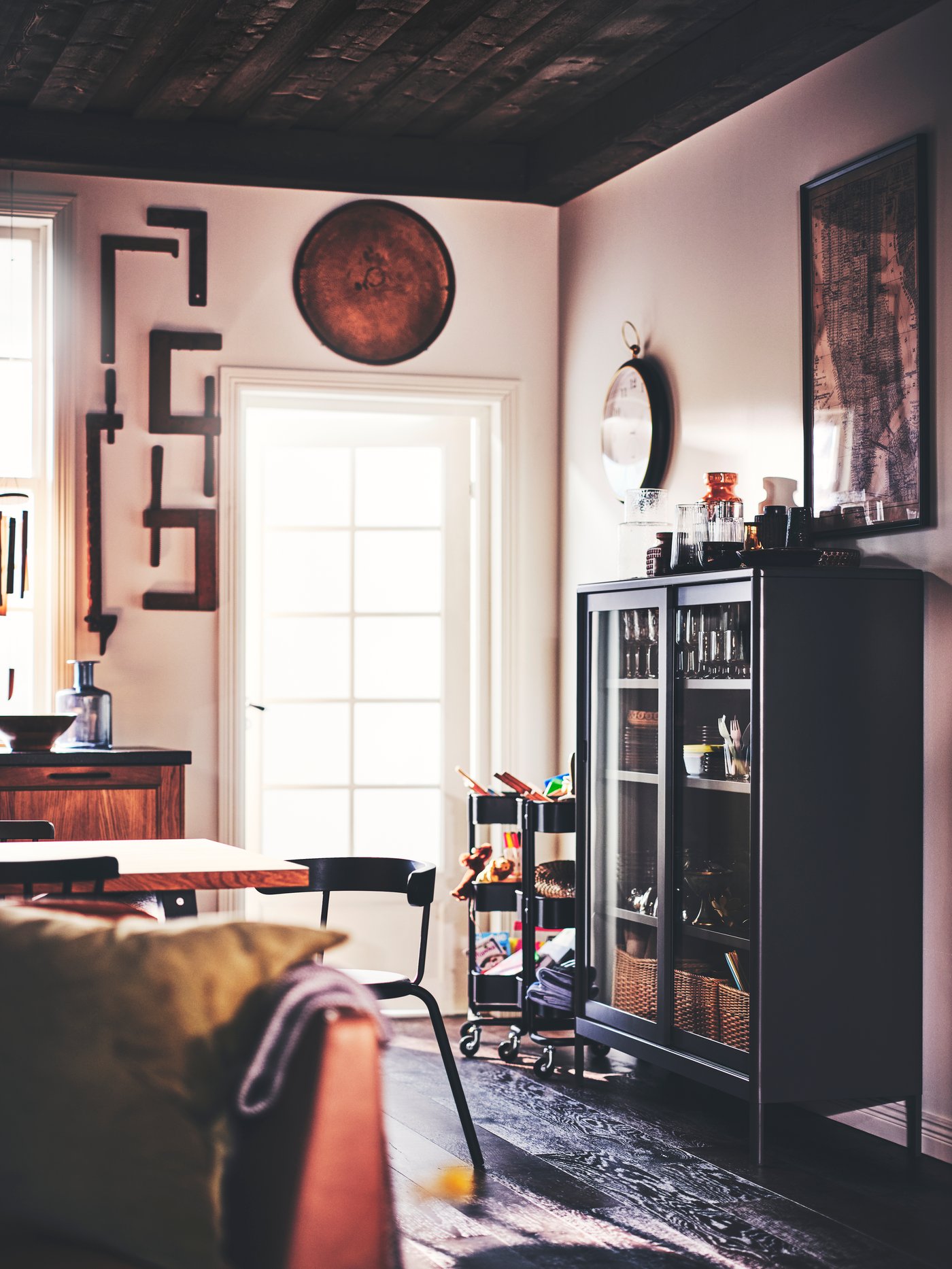 Salón elegante con gran puerta de vidrio y armario de acero gris oscuro con puertas correderas de vidrio con adornos.