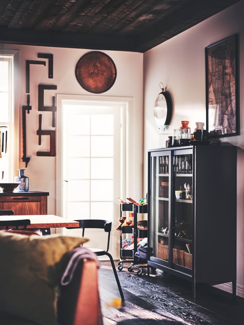 Classy living room with large glass door and dark grey steel cabinet with sliding glass doors holding decorations.