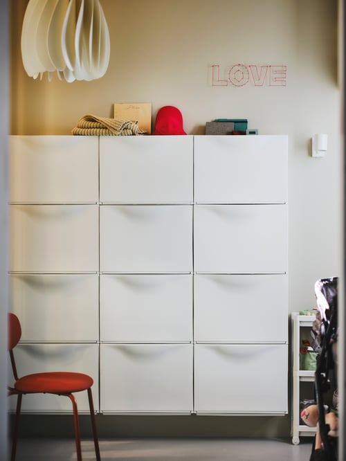 Hallway area featuring a white TRONES shoe cabinet with twelve compartments set next to a brown ÖSTANÖ chair.