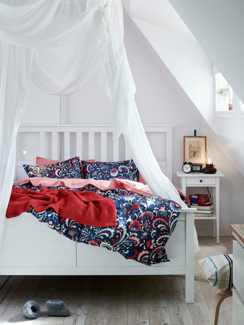 Weiß gebeiztes HEMNES Bettgestell mit weißem Betthimmel und Bettwäsche mit kräftigem blauen Muster.