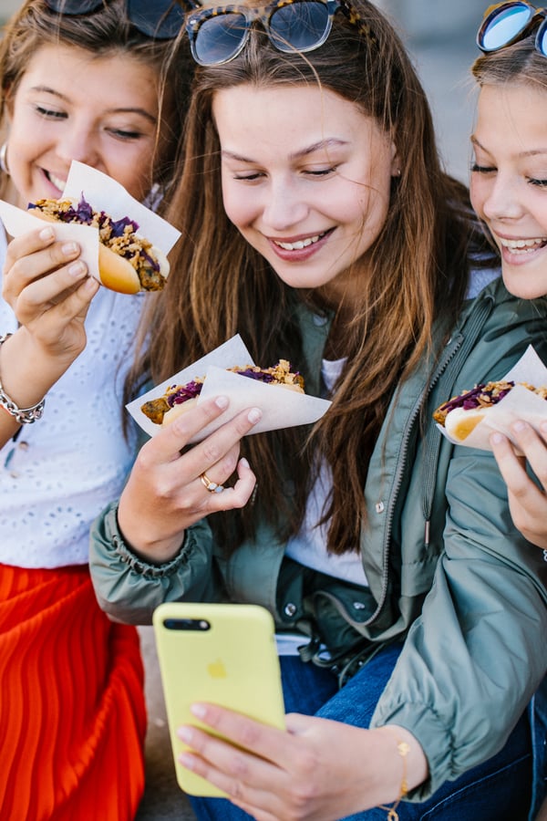Tre kvinder tager en selfie af dem selv der spiser veggie hotdogs.