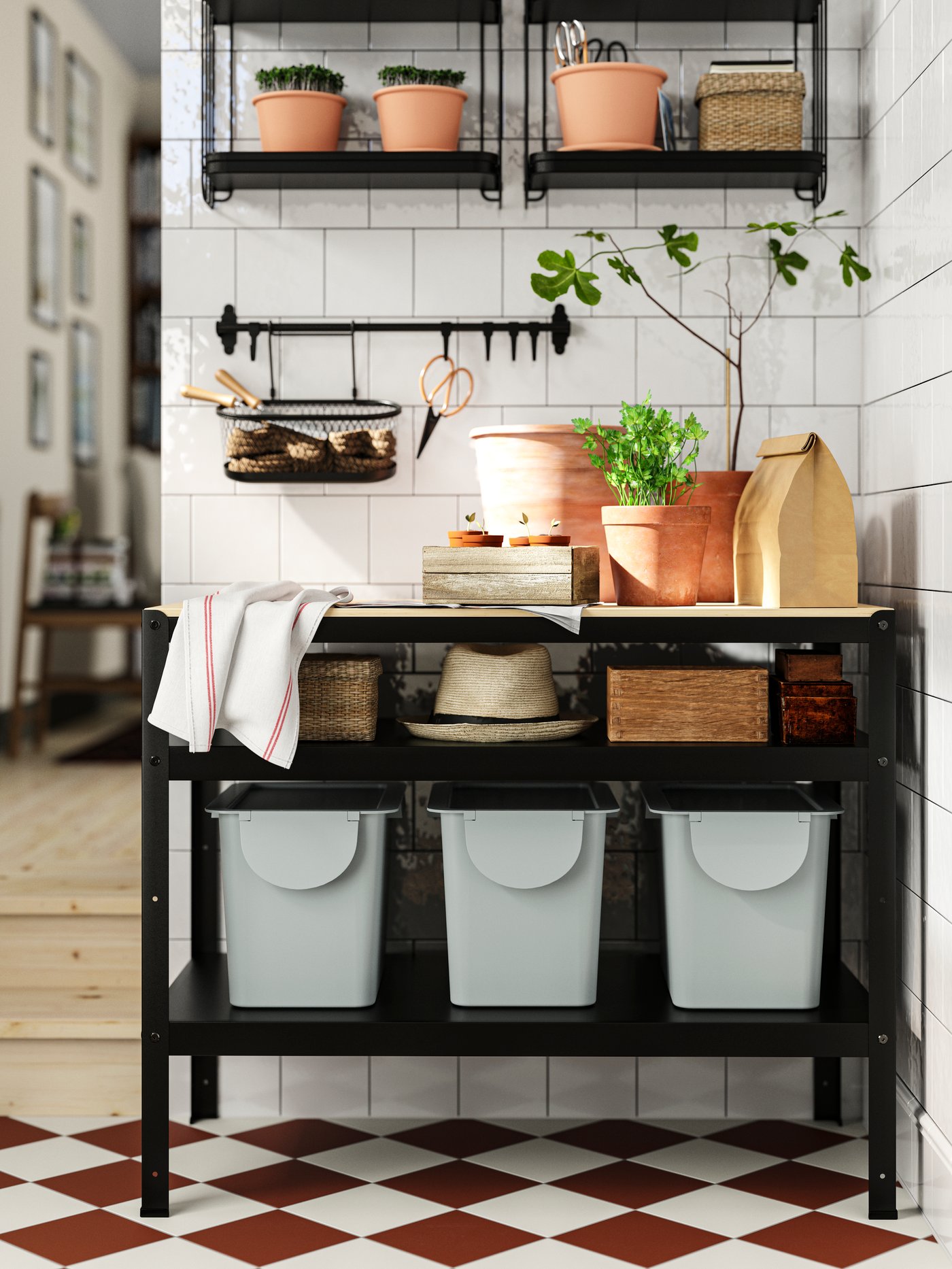 Na blacie ławy do pracy BROR znajdują się rośliny, doniczki i przybory ogrodnicze, a na dolnej półce stoją trzy szare kosze TRÖSKNING.