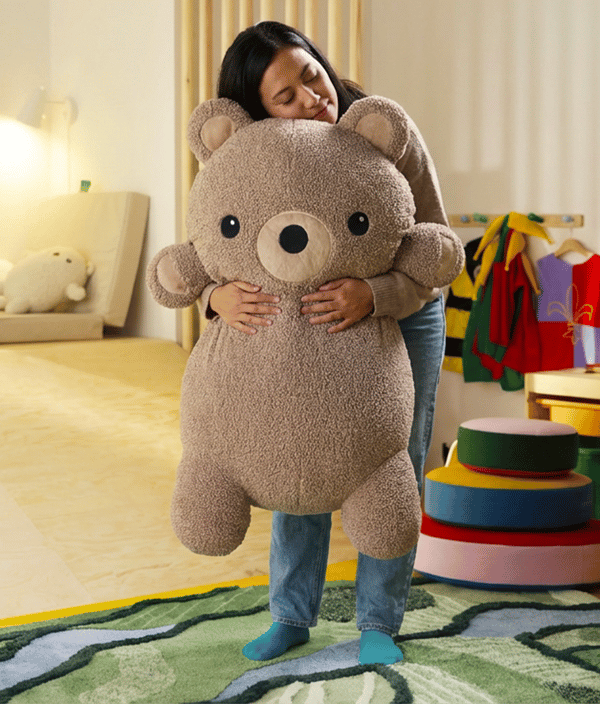 Femme tenant une peluche IKEA dans les mains.