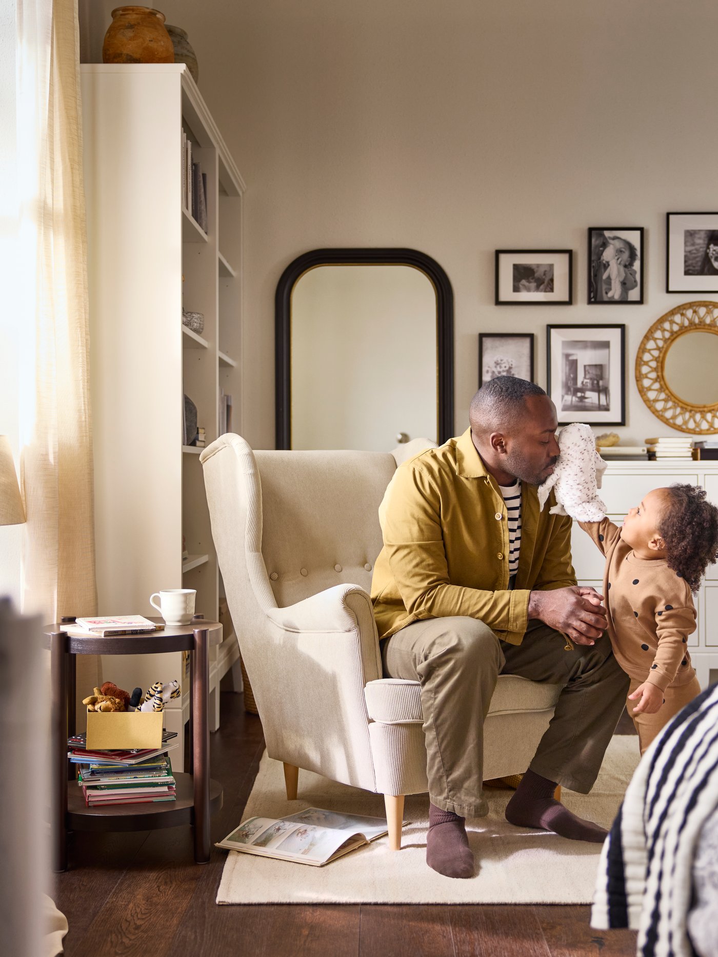 A father sitting on an armchair in a bedroom, with the child telling a story by the help of SKOGDUVA hand puppet soft toy.