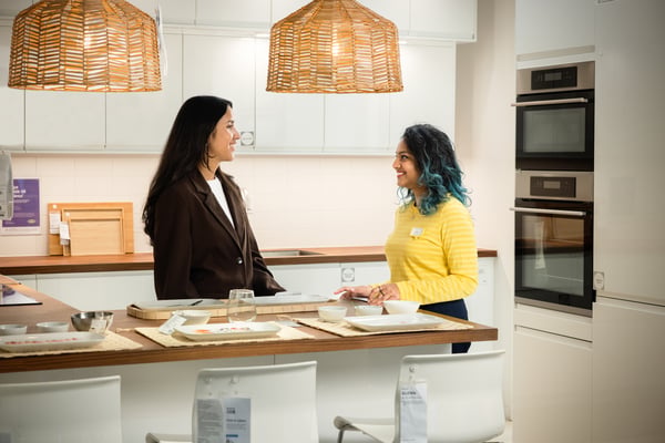 An IKEA staff member is helping a customer with kitchen planning advice