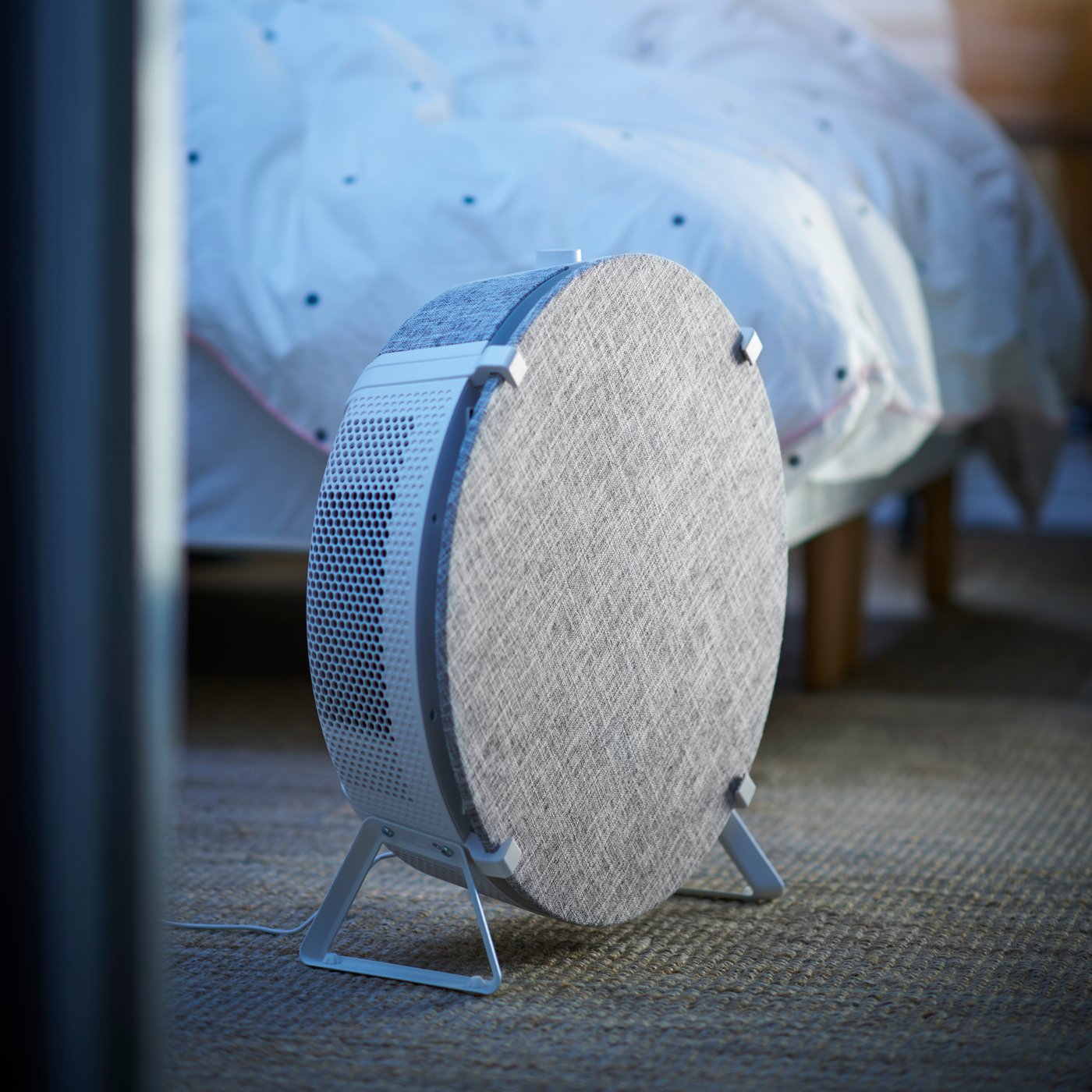 Kulatá čistička vzduchu STARKVIND v bílo-šedém provedení u postele.