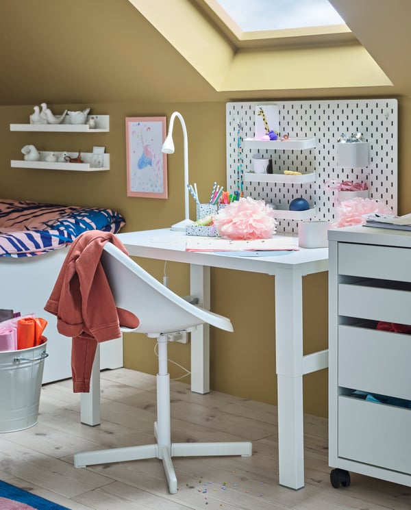 Un escritorio para niñas debajo de una ventana. Al costado del escritorio hay una cajonera MICKE de IKEA.