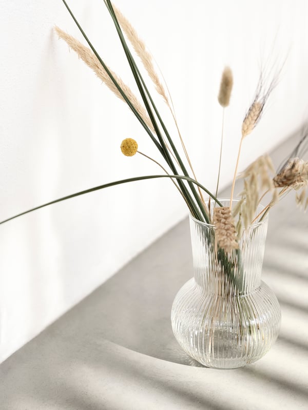 Close-up of rippled glass Scandinavian deco style vase with arrangement of reeds and grasses.