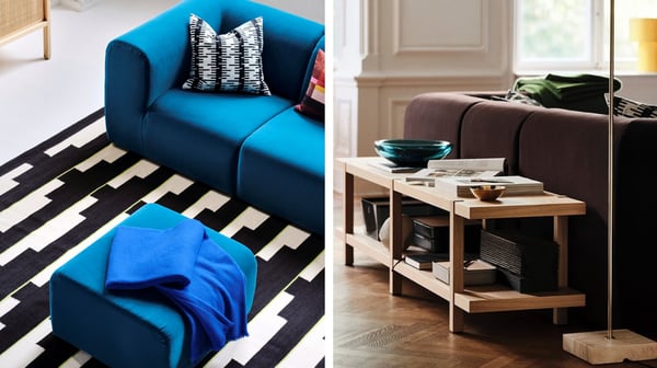 A living room with a blue sofa, a black‑and‑white striped rug, a wooden table and a light‑coloured wall with two windows.