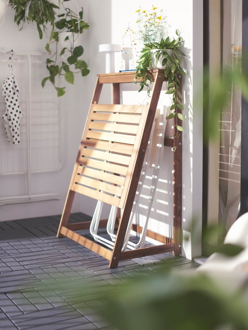 ブラウンのDJUPÖN ジューポーン 折りたたみテーブルの隣に植物や屋外用デコレーションがある屋外環境。