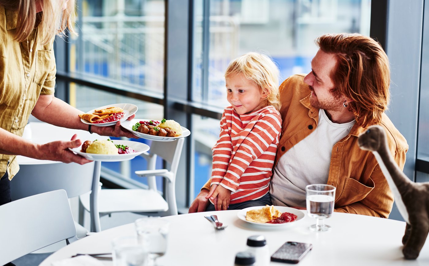 Ett barn sitter i en pappas knä i en IKEA restaurang.