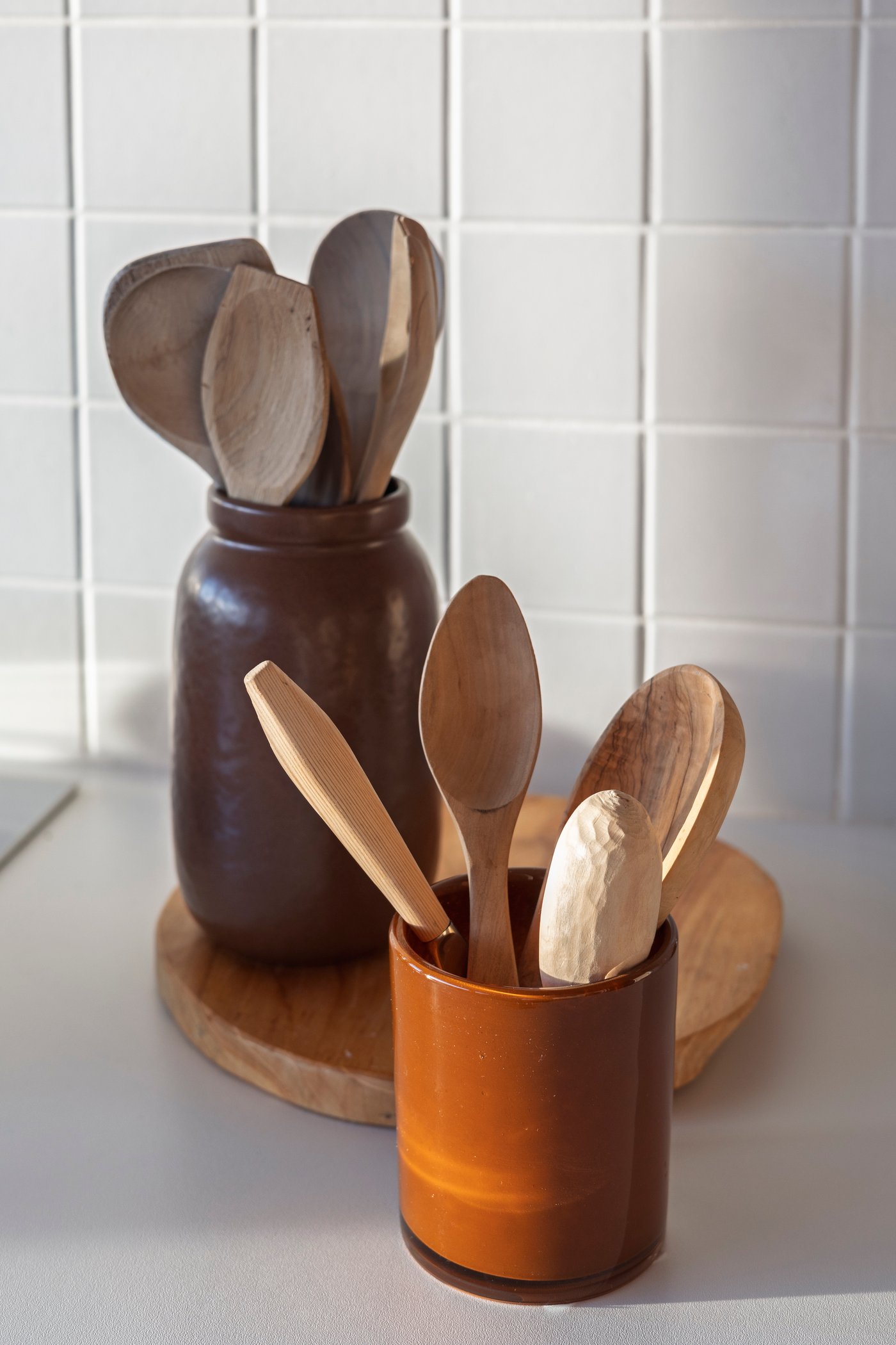En vase i keramikk huser kjøkkenredskapene i tre.