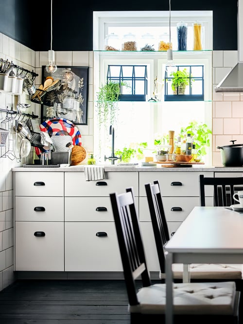 A kitchen with a base cabinet for sink with fronts and drawers, standard base cabinets, brown chairs, and a table.