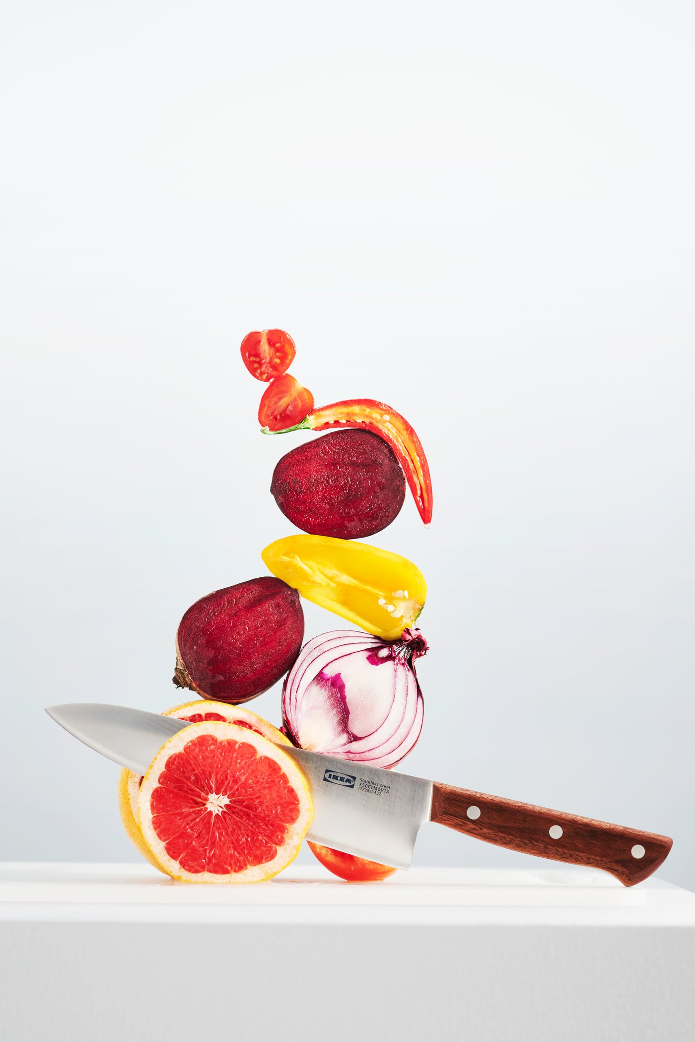 VARDAGEn kokkekniv omringe av frukt og grønnsaker.