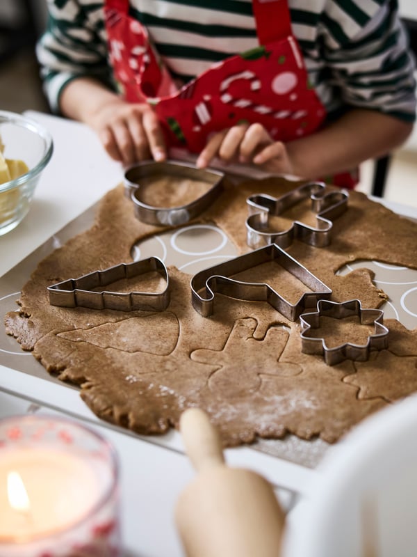 En person trycker ut pepparkakor från en deg.