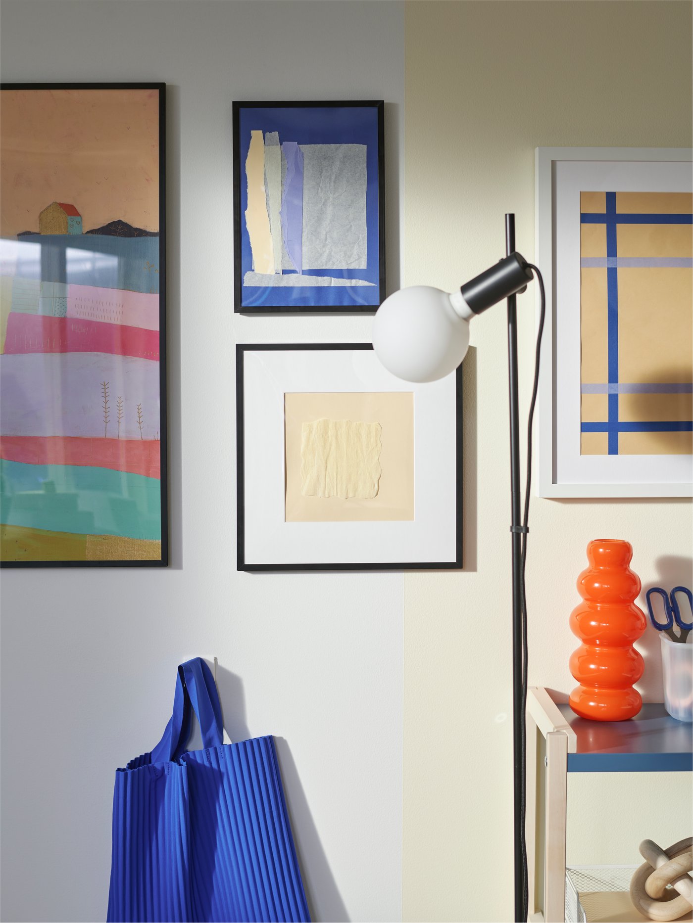A colourful BILD poster and graphic motifs in LOMVIKEN frames and a HÅRSLINGA/LUNNOM floor lamp with a decorative light bulb.