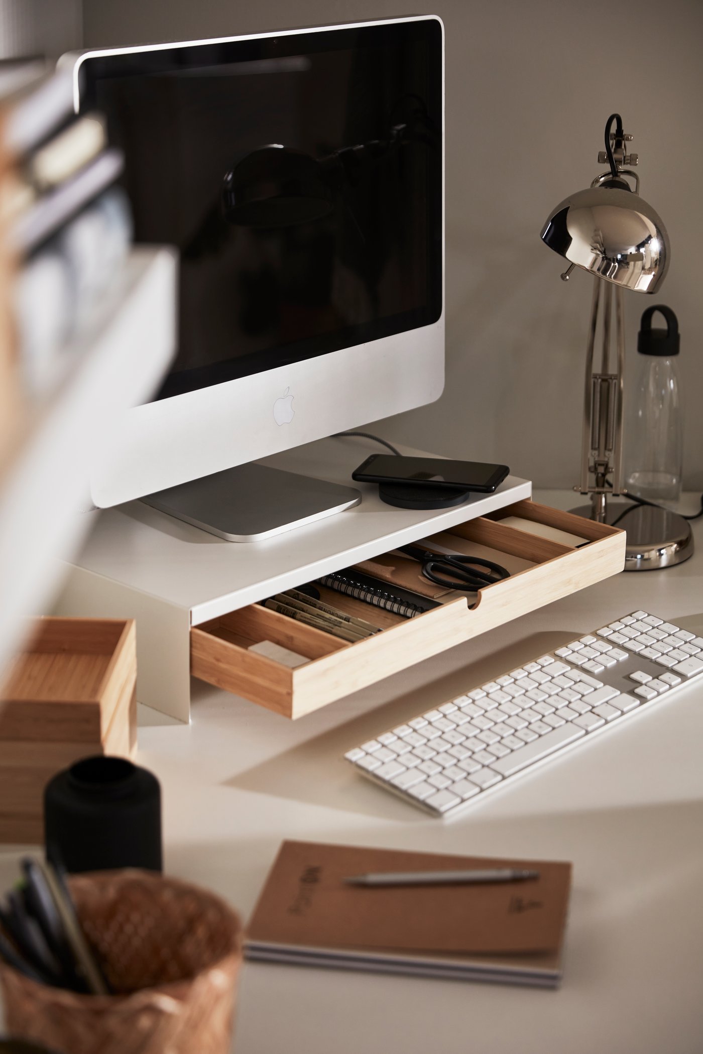 Una scrivania con un monitor e un supporto per monitor con cassetto