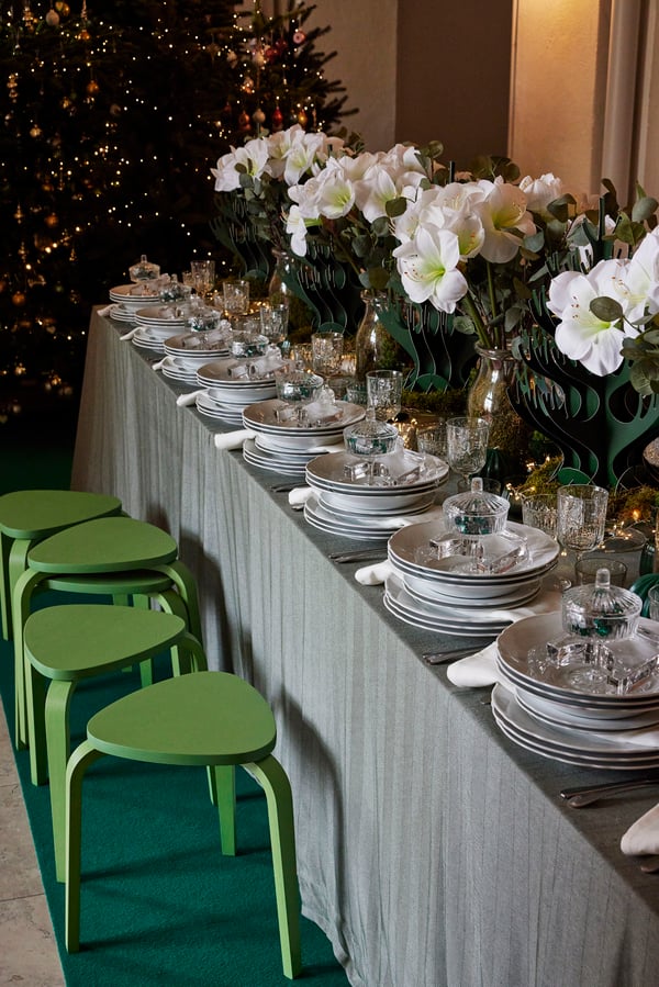 Festligt dækket julebord med flere grønne skamler og hvide blomster.