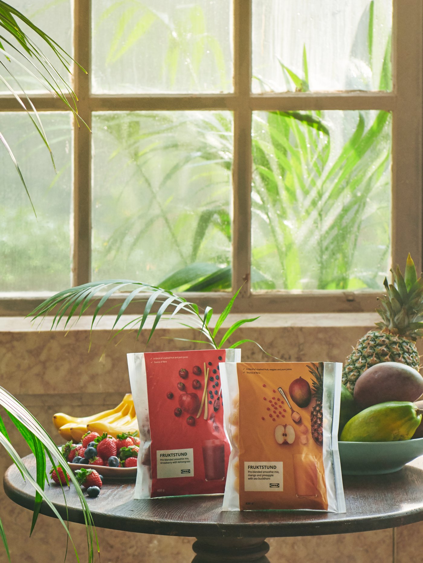 Des paquets de frappé prémélangé FRUKSTUND, dont un mélange jaune tropical et un mélange rouge fraise, placés sur une table.