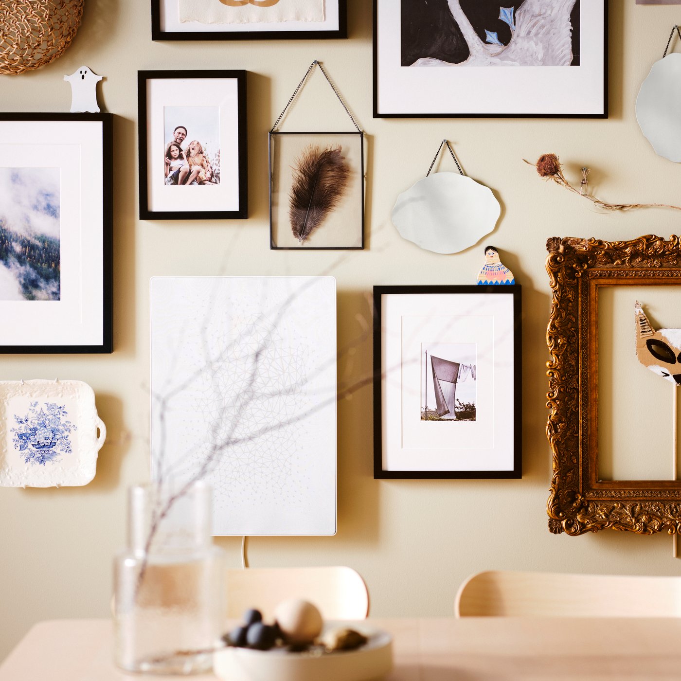 A picture wall over an ash RÖNNINGE table, with black RIBBA and LOMVIKEN frames plus other frames and decorative items.