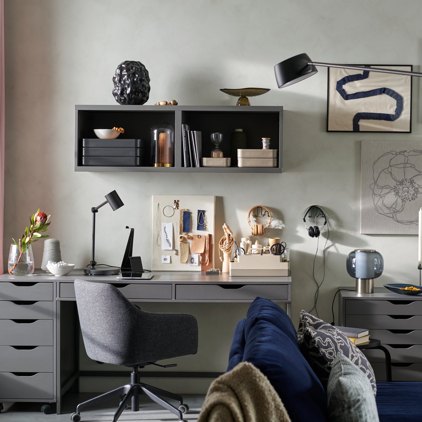 Dnevna soba z zofo, stenskimi umetninami in kotičkom za hobije, ustvarjenim s temno sivo pisalno mizo in enotami za shranjevanje iz ALEX serije.