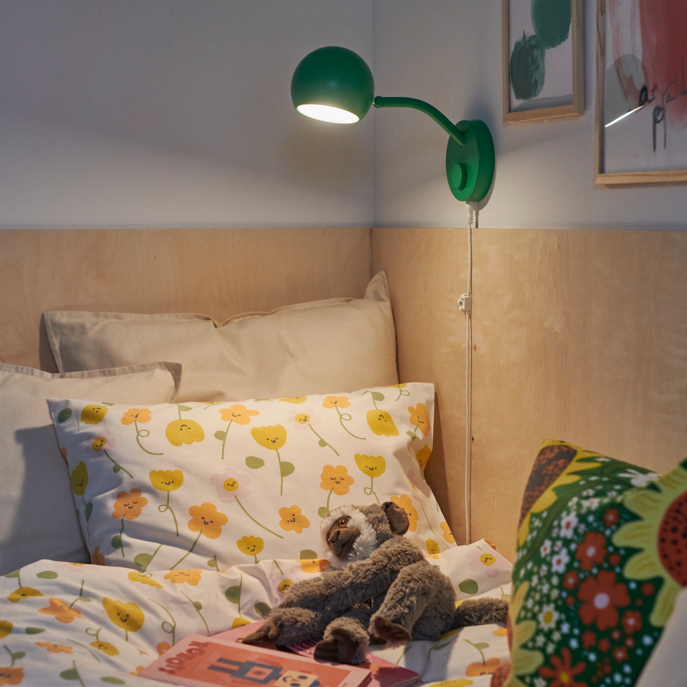 A bedroom featuring a green KORVSNÖRE lamp and a BARNDRÖM duvet cover set with a flower pattern, arranged on a bed.