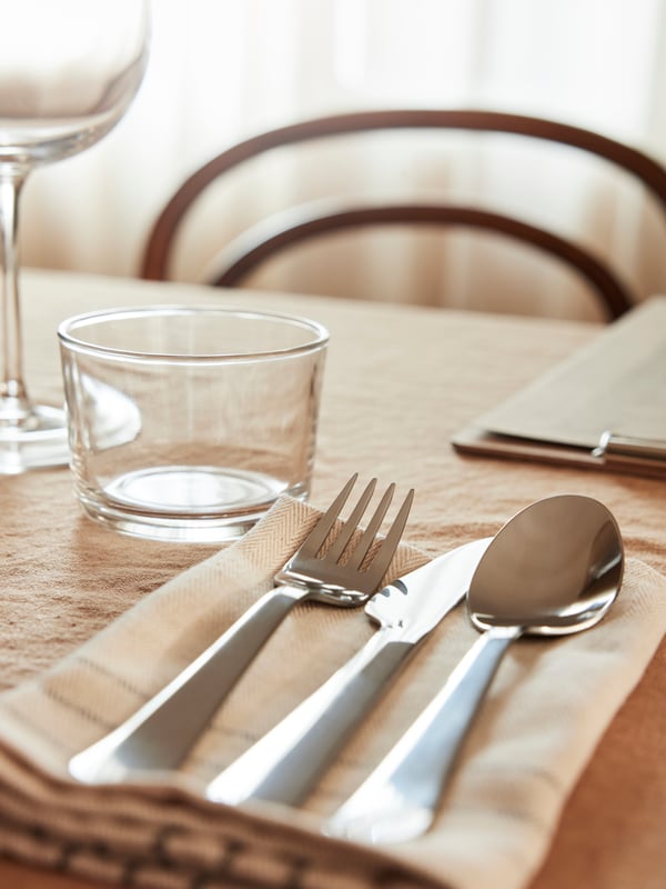 A black and white striped place mat with a napkin on it holding a knife, two forks and two spoons from a DRAGON cutlery set.