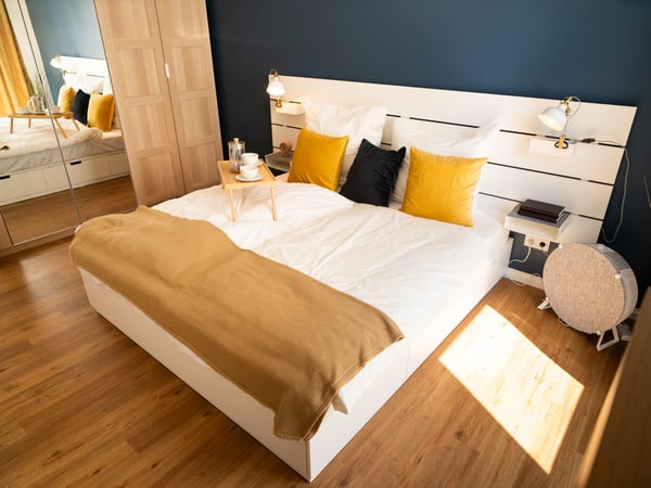 Ein Bett mit einer gelb-beigen HUMLEMOTT Tagesdecke.