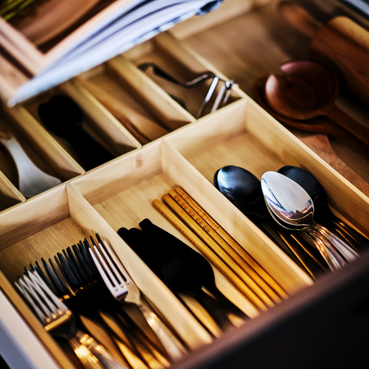 Un cassetto della cucina aperto con all'interno il portaposate UPPDATERA con all'interno posate e accessori per cucinare