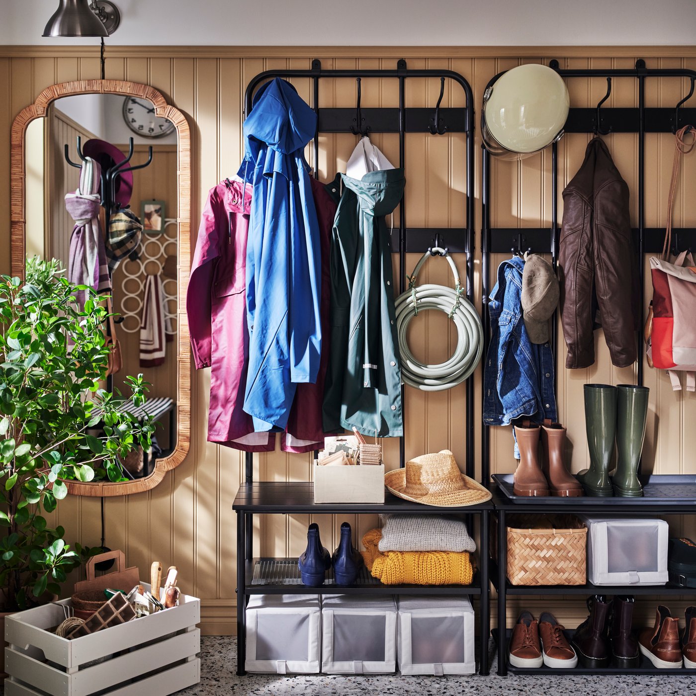 Two black NIPÅSEN coat racks and benches with shoe storage in a light brown mudroom with a painted KNAGGLIG box on the floor.