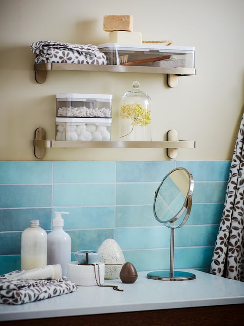 Wall section with bathroom accessories neatly arranged in BROGRUND boxes, set on wall-mounted, individual shelves.
