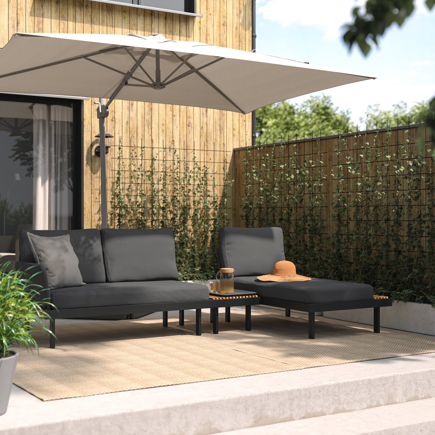 Ein Outdoor-Sitzgruppe REVSKÄR für 3 Personen in Anthrazit/Frösön/Duvholmen Dunkelgrau. Der REVSKÄR Couchtisch als Ablage zwischen Recamiere und Sofa integriert.