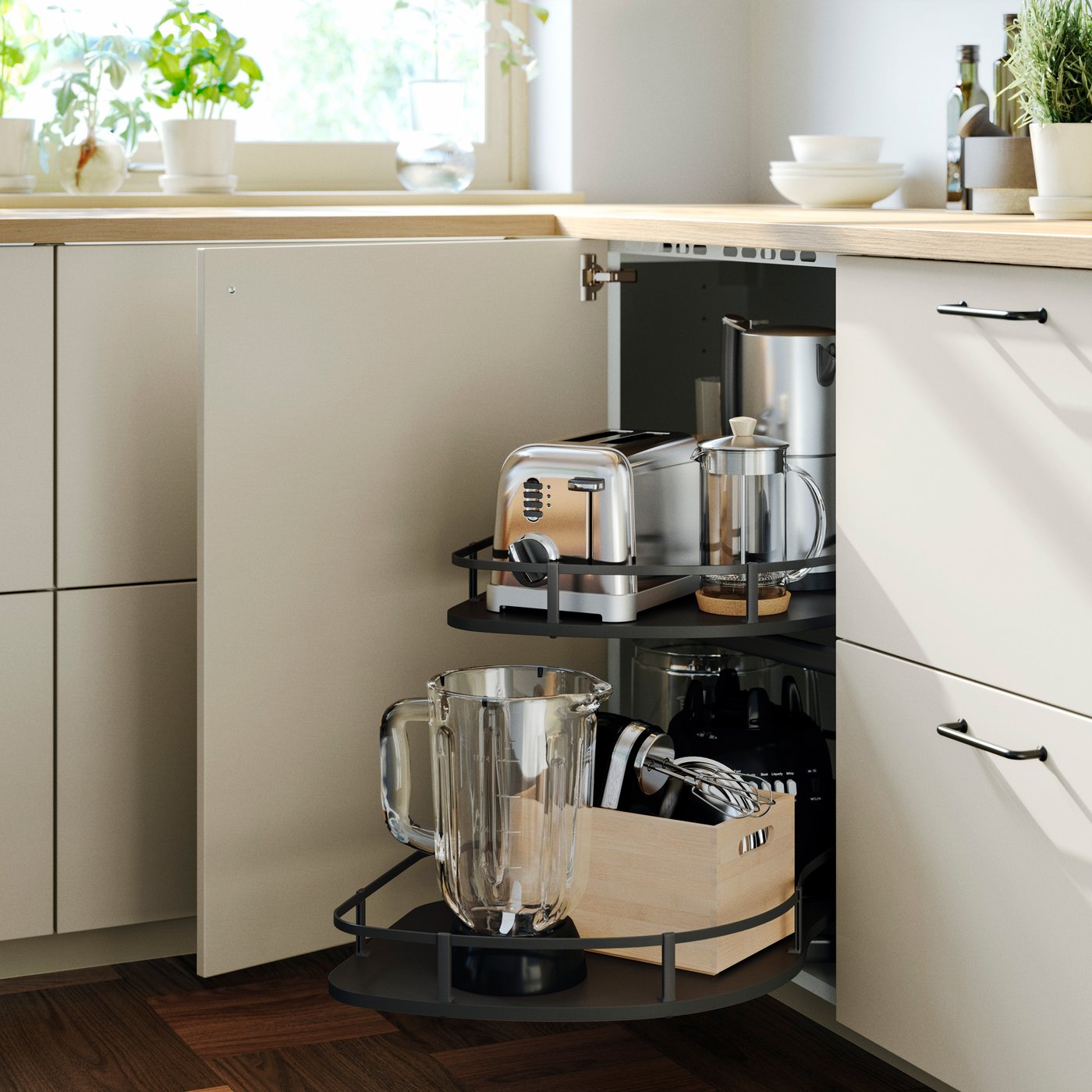 The open door of a METOD base cabinet reveals an UTRUSTA corner pull-out unit containing a number of kitchen appliances.