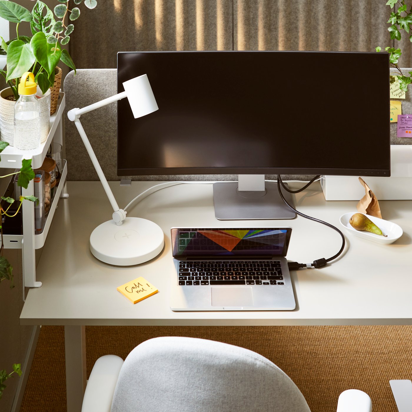 A workspace centred around a TROTTEN sit-stand desk between a white TROTTEN sliding-door cabinet and a window with plants.