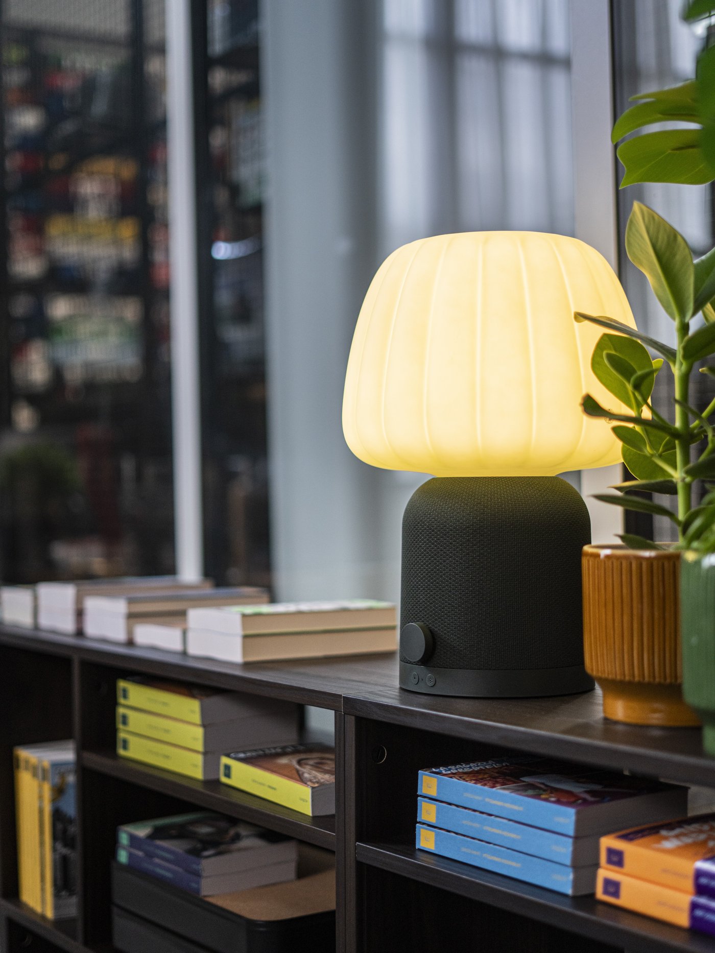 Studio con libreria nera e sopra una lampada/cassa Bluetooth KUNGLASS verde scuro.