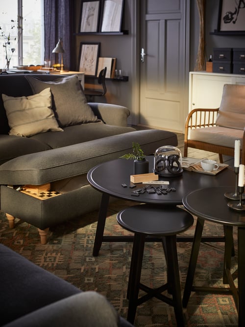 Living room with a grey bench with storage and turned legs placed next to a nest of table set of 2 and an armchair.