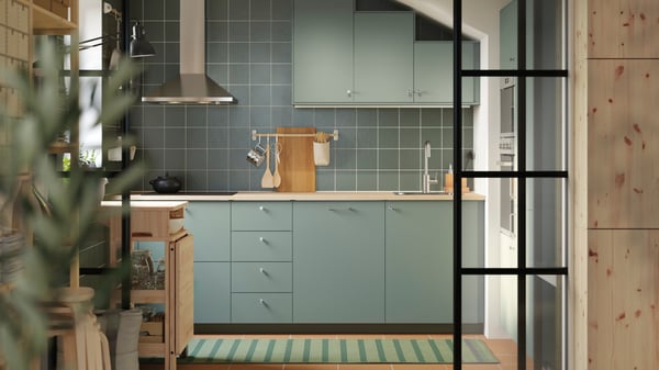 A kitchen has base and wall cabinets with matt grey green NICKEBO fronts and a RESARÖ mobile drop-leaf table with storage.