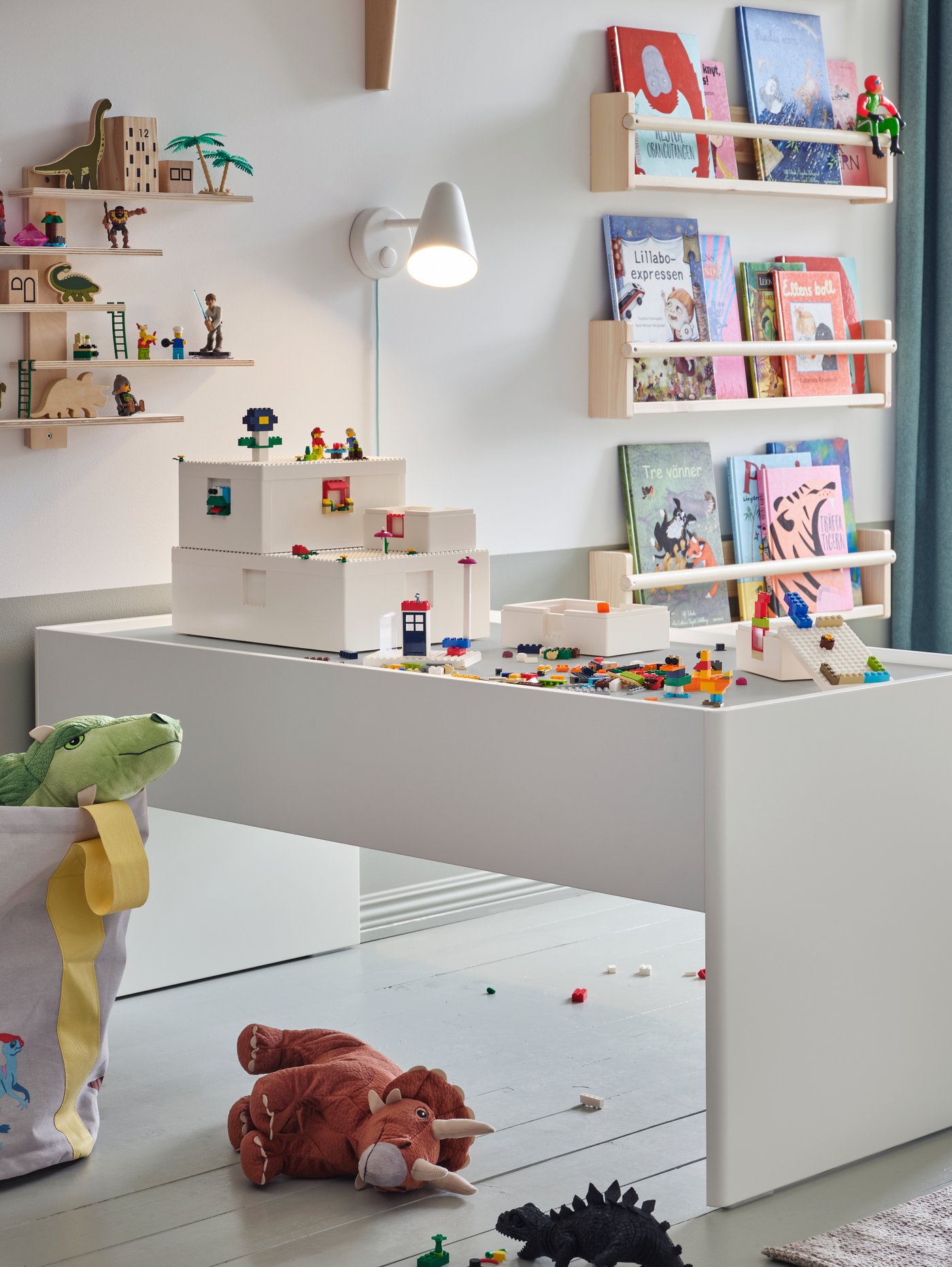 Habitación infantil con mesa de actividades blanca con cajón de almacenaje y superficie laminada duradera, cajas LEGO y juguetes encima.