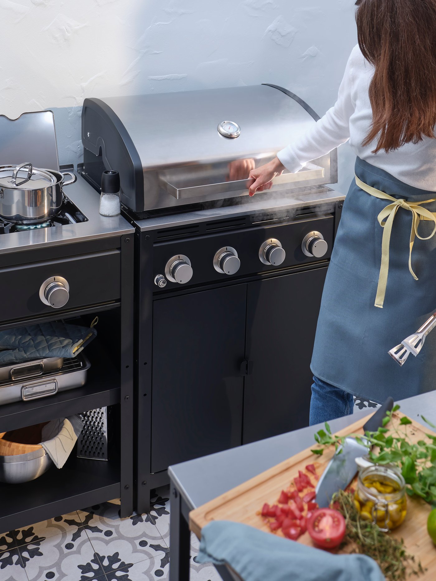 A black/stainless steel GRILLSKÄR gas barbecue in an outdoor kitchen
