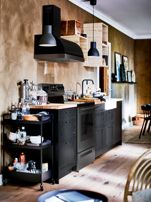 Kitchen with a base cabinet for sink and waste with two fronts, an open cabinet, pendant lamps, a trolley, and base cabinets. 