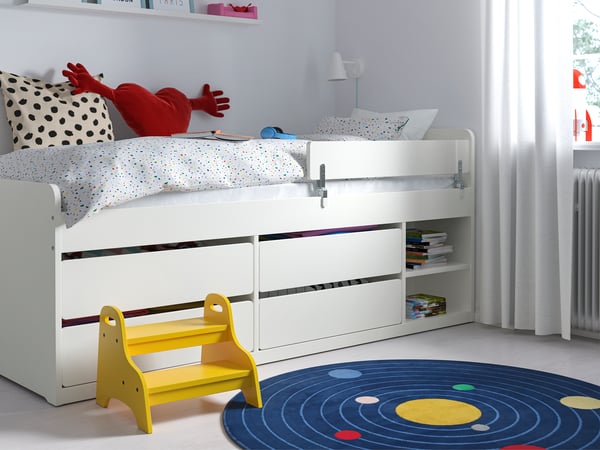 White kids storage bed with four drawers and an open shelf area in a kids room.
