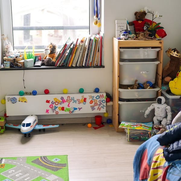 A bright children's room with IKEA TROFAST storage filled with toys and books in the window.