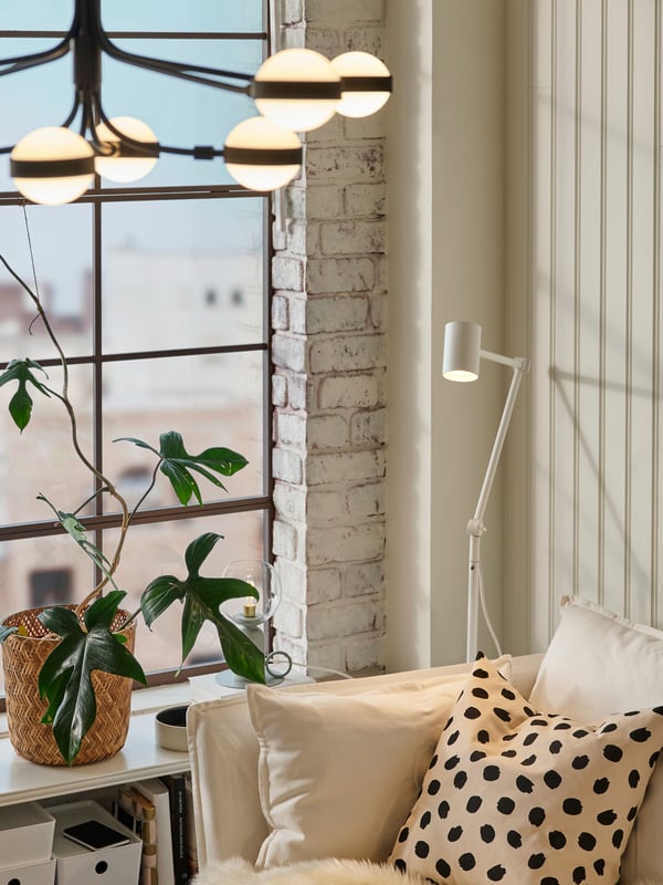 a room with a chandelier hanging over the couch and a plant
