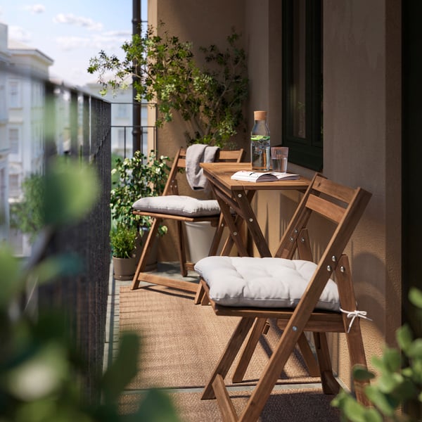 Two foldable NÄMMARÖ chairs with KUDDARNA chair cushions stand on either side of a NÄMMARÖ folding table.