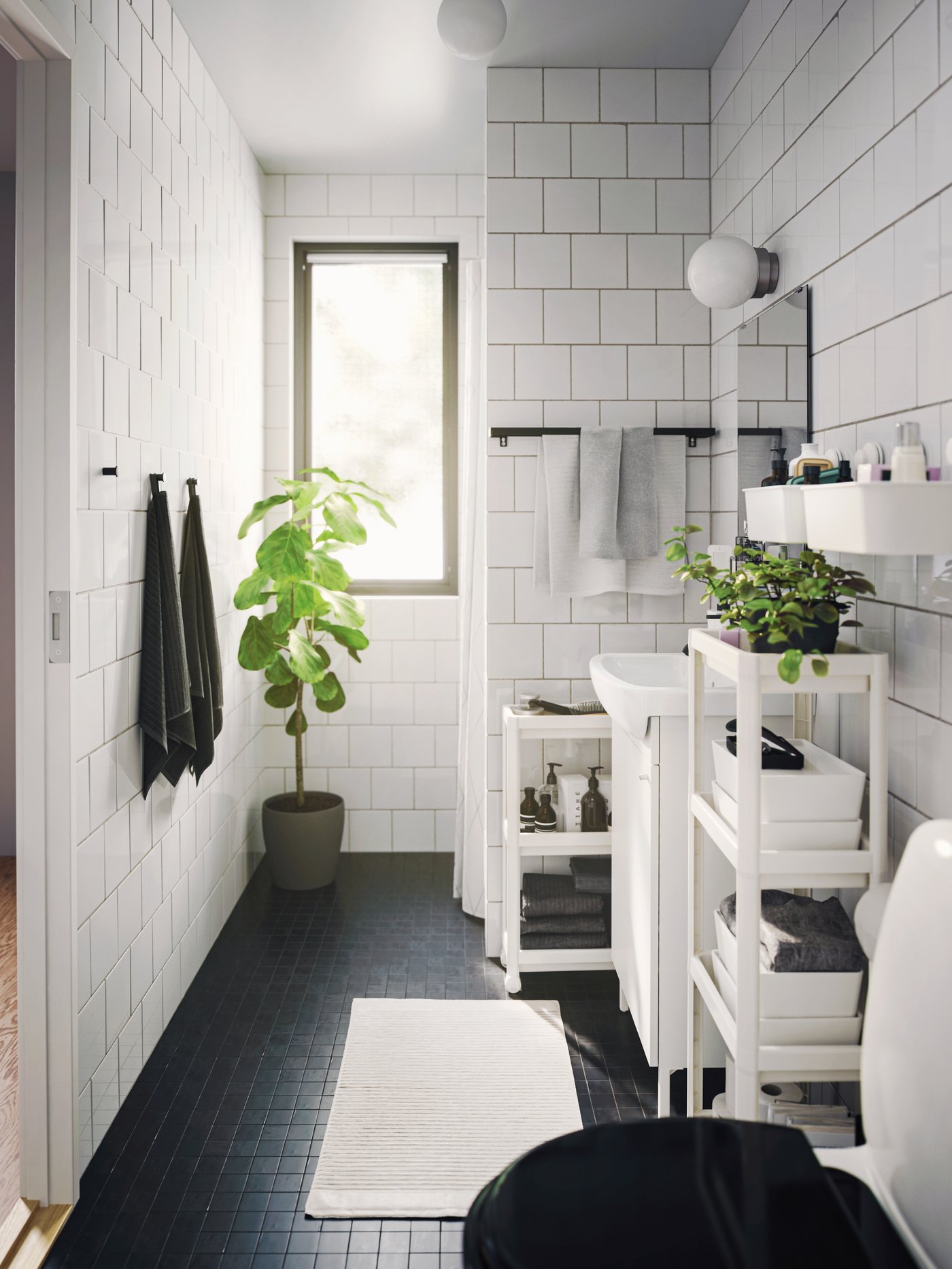 Ein verschönertes Badezimmer mit verschiedenen platzsparenden Aufbewahrungen, Rollwagen und Zimmerpflanzen.